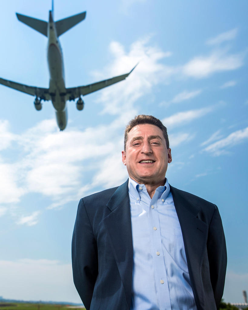 Lance Sherry, a professor in systems engineering at Mason, stands in front of an airplane that is flying in the sky