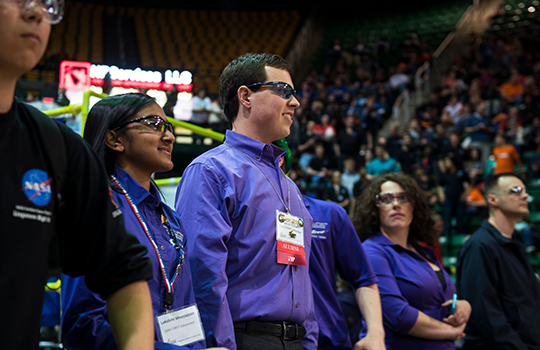 Alumni Lakshmi Meyyappan (on left) and Jacob Cohen, Computer Engineering '14, mentor and celebrate team ILITE Robotics after winning the Chariman's award at the FIRST Robotics Competition for the greater DC region. Photo by Evan Cantwell/Creative Services/George Mason University